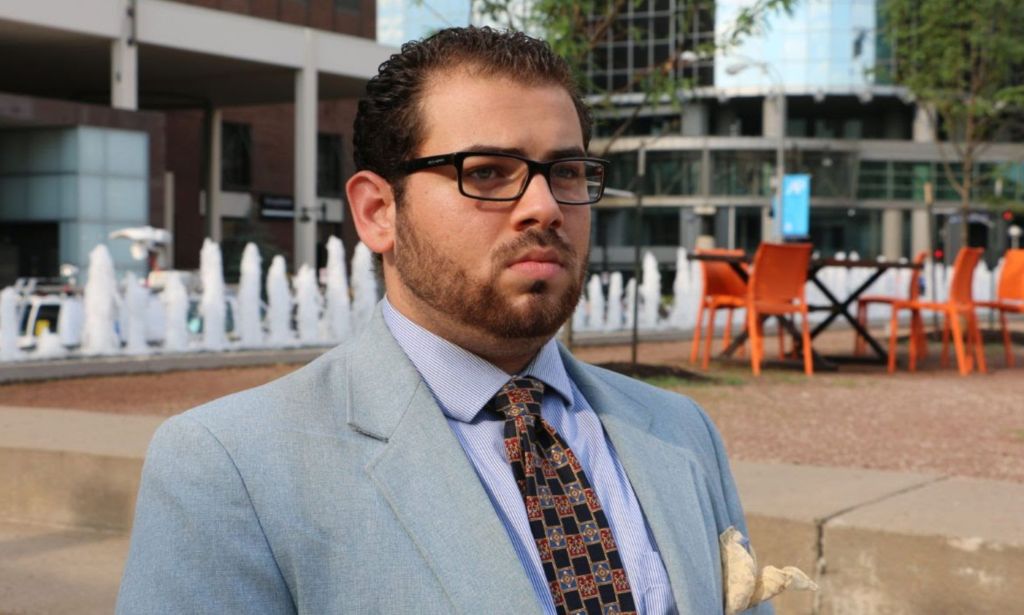 Wajeeh Gay Lion, an openly gay activist from Saudi Arabia, wears a suit and tie as they stand outside