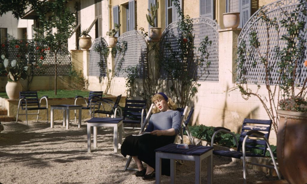 British trans woman Roberta Cowell wears a shirt and skirt as she lounges on a chair in France