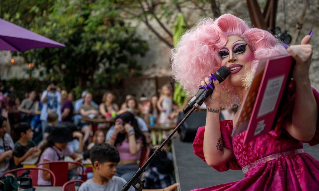 A drag queen holds up a book as she reads to kids in the audience at an event in Texas as Republican lawmakers try to ban such kid-friendly events