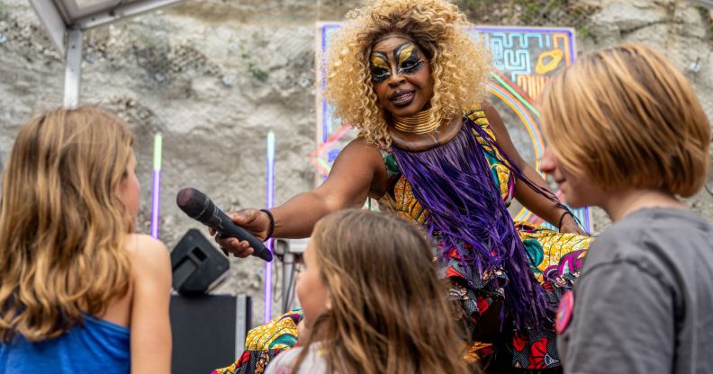 A Black drag queen stands on stage as she holds out a microphone to kids in the audience at an event in Texas as Republican lawmakers try to ban such kid-friendly events