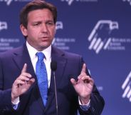 Florida governor Ron DeSantis wears a suit and tie as he gestures with one finger raised upwards on both hands during a speech