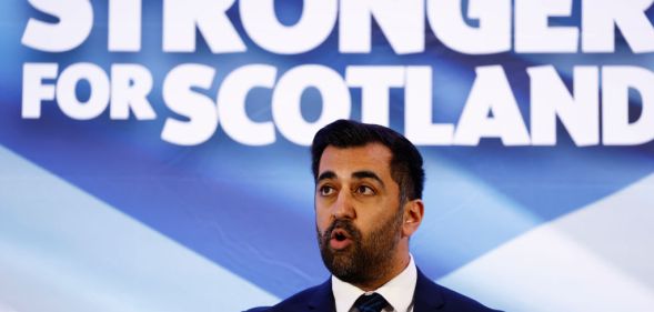 Humza Yousaf in font of a Stronger for Scotland sign