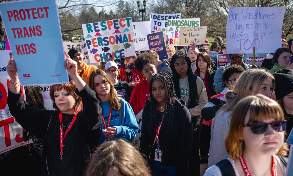 A crowd of people, many of whom are young, hold up signs in support of the LGBTQ+ community and trans youth as they protest the passing of SB 150 at the Kentucky state capitol.