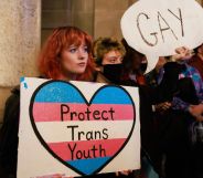 Protesters hold a placard that says, "Protect trans youth" and "Gay" as they protest against Republicans attacking LGBTQ+ rights including education on queer topics and trans healthcare