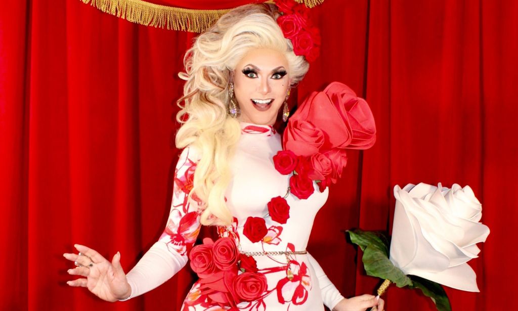 Tennessee drag queen Bella DuBalle, who has been fighting anti-LGBTQ+ bills and the state's drag ban, wears a white dress with red rose details and holds a giant prop white rose