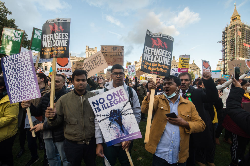 Protestors hold placards and react to the speakers during a rally called by Amnesty International and others in support of refugees in Parliment square on October 20, 2021.