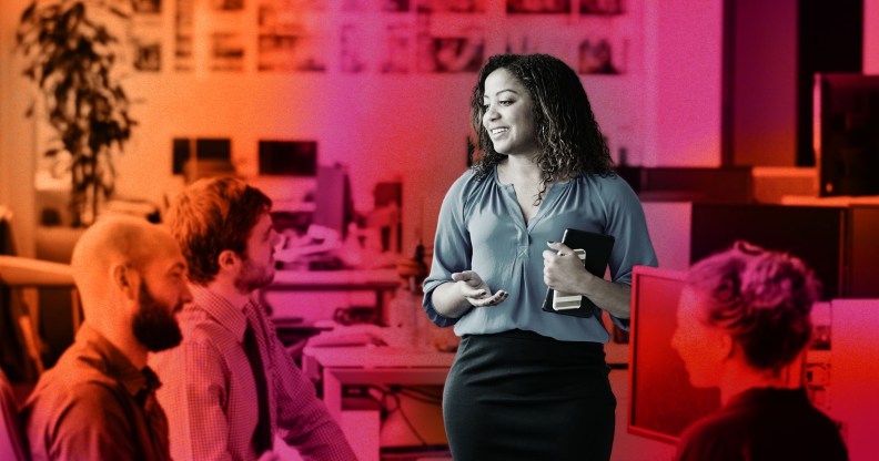 This is a stylised image of a woman speaking to her colleagues at work. Her image is emphasized over a red an orange background