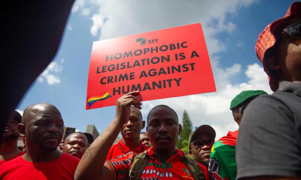 A proptester holds a sign that reads: homophobic legislation is a crime against humanity