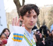 Singer Troye Sivan waves to the camera at 2023 Paris Fashion Week.