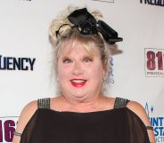 Victoria Jackson gawps at camera wearing black dress and black ribbon in her hair.