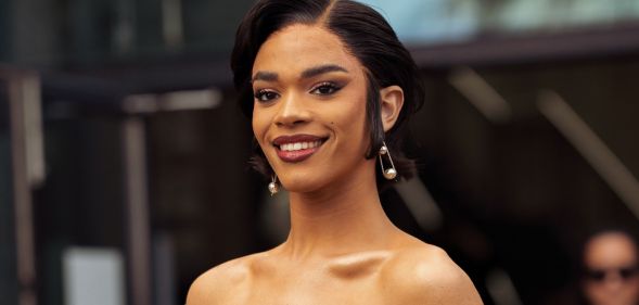 Yasmin Finney wears a black dress, pearl earrings and smiles at the camera.