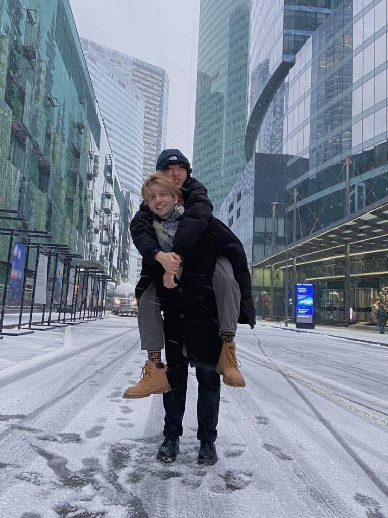 Russia based LGBTQ+ blogger Haoyang Xu piggy backs on his boyfriend Gela Gogishvil's back as they pose for a picture outside