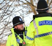 Two police officers wear the yellow, blue and black uniforms associated with law enforcement in England and Wales as they stand at the scene of a crime