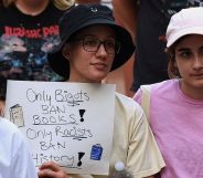 A person holds a sign reading "only bigots ban books, only racists ban history."