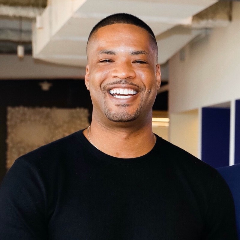 This is a corporate headshot of Andrew McCaskill. He is is wearing a black shirt. He is smiling and his hair is cropped short.
