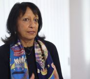 Kishwer Falkner, wearing a multi-coloured scarf, speaks in a white room.