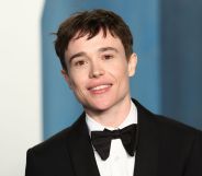 Elliot Page wears a black suit and bow tie while smiling at the camera.