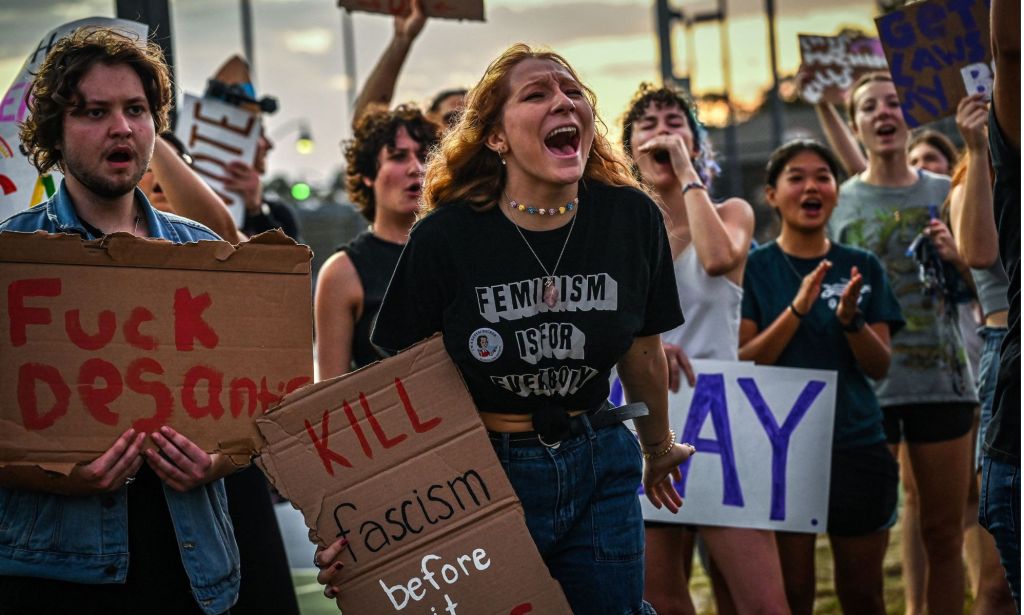 Protestors condemning Ron DeSantis' LGBTQ+ tirade in Florida, with signs reading "fuck DeSantis" and "kill fascism."