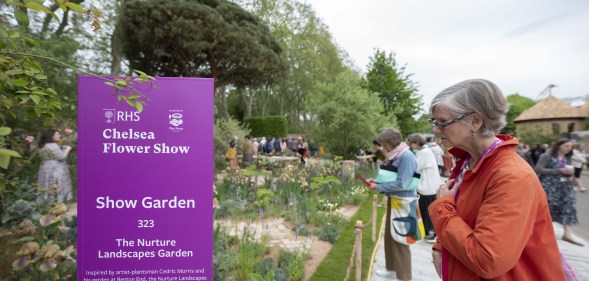 Woman seen looking at flowers next to a Chelsea Flower Show sign