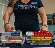 A member of Moms for Liberty rests her knuckles on the tops of a stack of books.