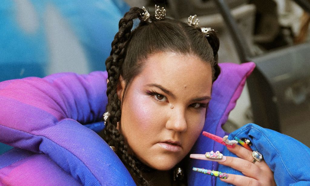 Eurovision star Nretta in a purple and blue coat and long colourful nails.