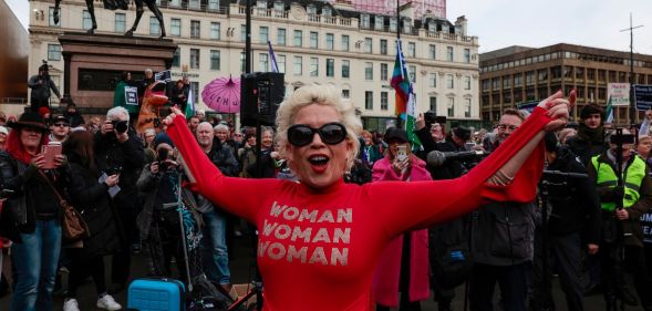 Anti-trans campaigner Posie Parker stands at a rally wearing a top reading "woman, woman, woman"