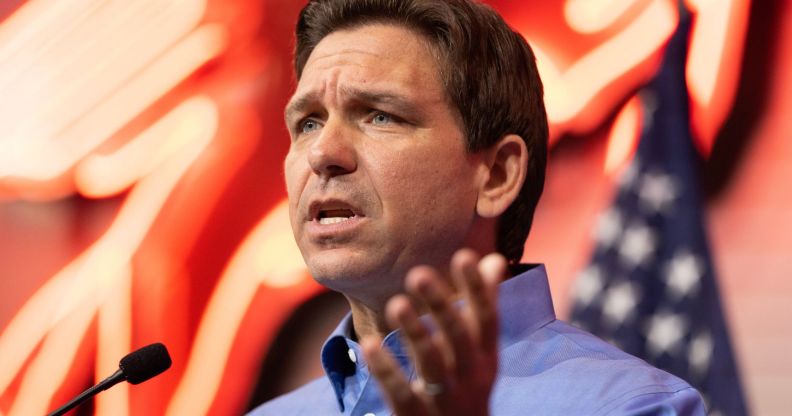 Ron DeSantis speaking to a crowd, with lights and an American flag behind him.