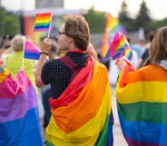 Wrapped in bisexual flag and pride flags this trio are watching a gay pride event