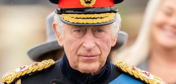 King Charles III wears military dress as he stands amid a crowd preparing for his coronation ceremony