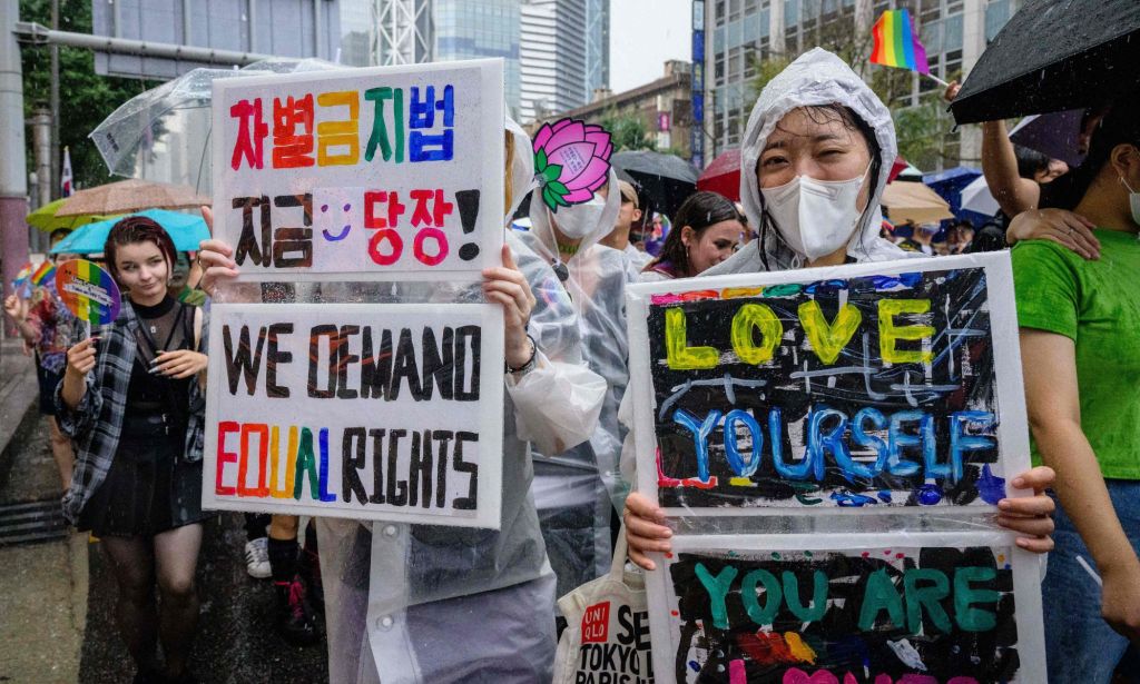 People hold up signs reading 'We demand equal rights' and 'love yourself' during an LGBTQ+ festival in South Korea