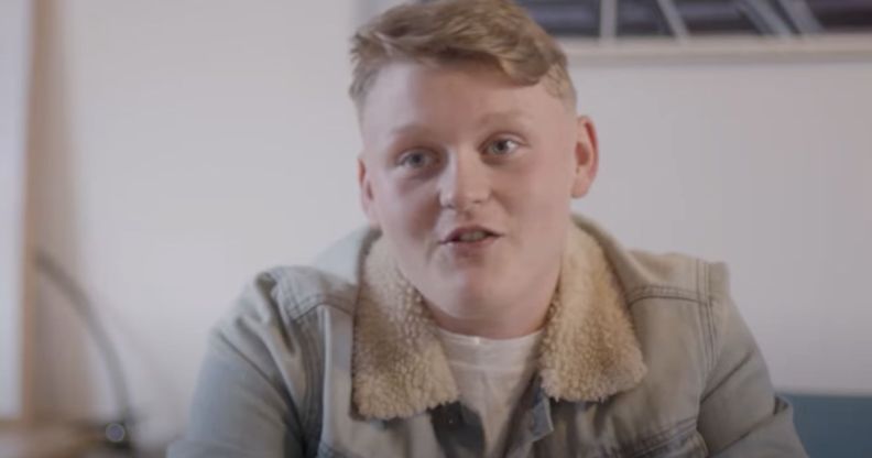 Trans teen Kai wears a white shirt and tan coloured jacket as he is interviewed for a film project by Fox Fisher and My Genderation