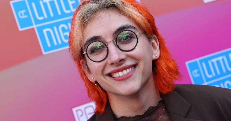 Non-binary actor Mason Alexander Park wears a black top and jacket as they smile for the camera