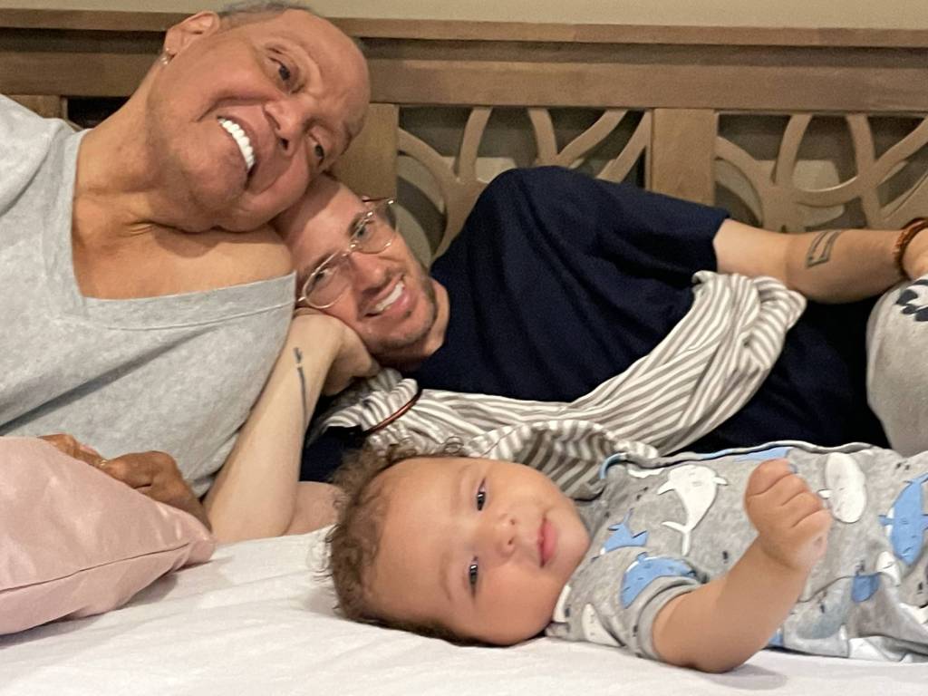 Black trans activist Miss Major Griffin-Gracy poses on a bed with her partner and baby with her as they all smile