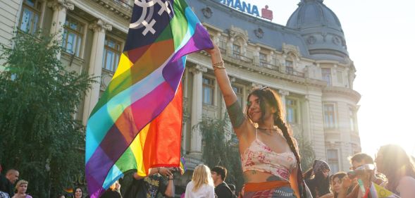 A person holds a Pride flag at Bucharest Pride.