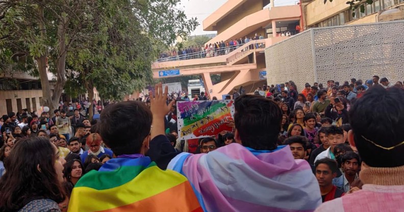 A group of Indian marchers at a Pride Parade, one draped in a transgender flag, the other in a pride flag.