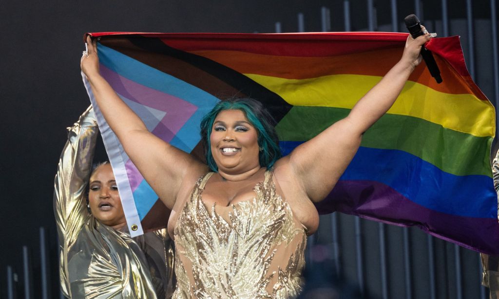Lizzo holding an LGBTQ+ progress flag.
