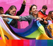 People marching in Pride, holding Progress Pride flags