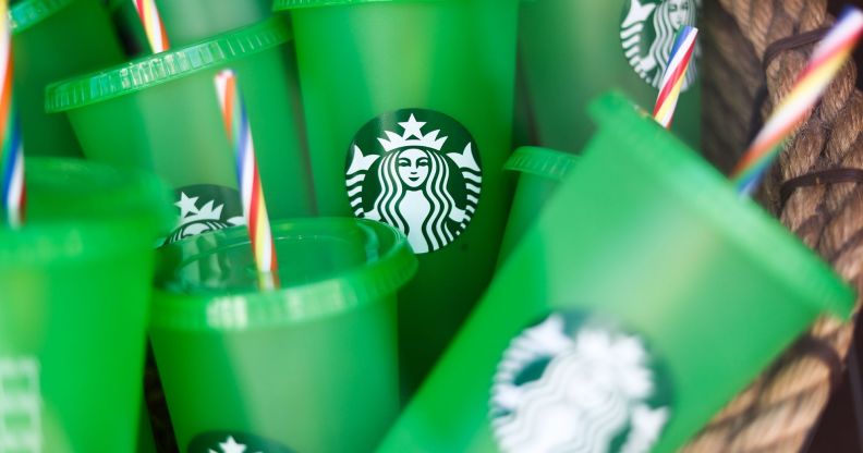 A set of green Starbucks brand cups with red, white, and blue straws in a pile together.