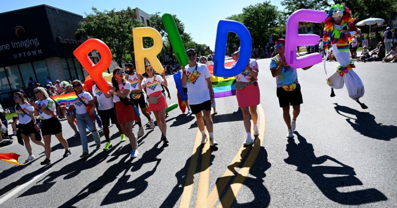 Revellers carry rainbow-coloured balloons that spell out PRIDE at a Pride parade in Denver, Colorado on June 25, 2023