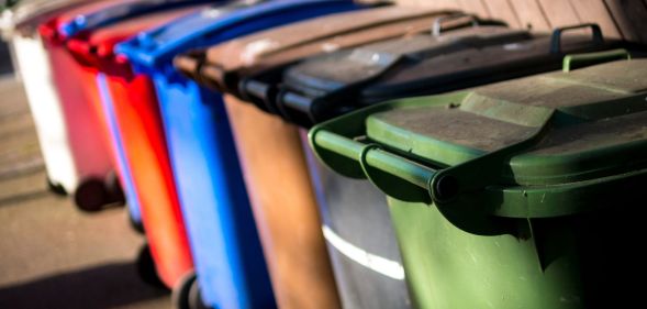 A set of UK wheelie bins, each a different colour, lined up against one another.