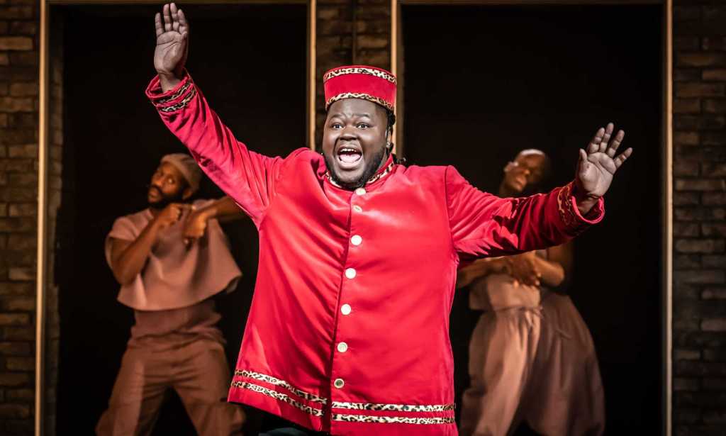 Kyle as Usher, a fat Black man wearing a red theatre usher costume