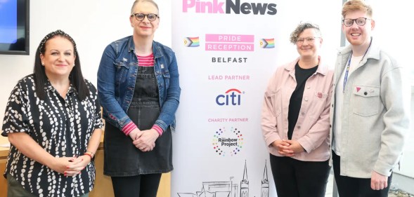 From left to right, Cara McCann, Kirsty Mulholland, Liz Skelcher and Odhrán Devlin at a Citi community lunch which was hosted in partnership with PinkNews. They are standing around a PinkNews banner which advertises the Belfast reception in partnership with Citi.