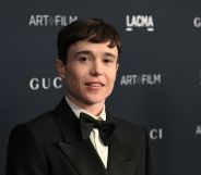 Elliot Page looks at the camera while wearing a white shirt, black bow tie and black suit jacket