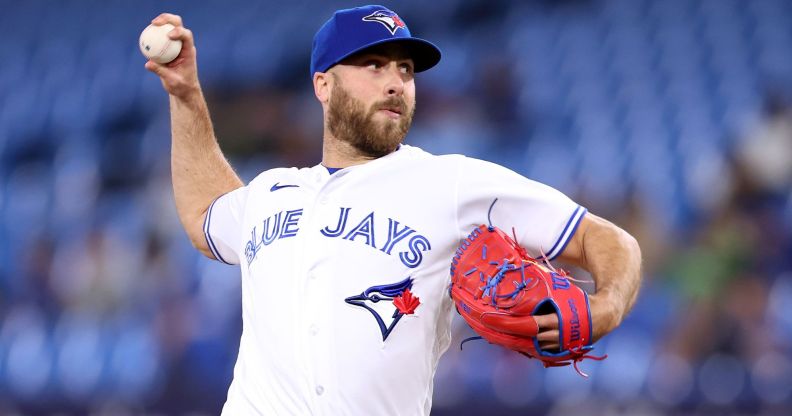 Toronto Blue Jays relief pitcher Anthony Bass wears a white uniform and blue baseball cap as he throws a baseball somewhere off screen