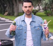 Ben Shapiro holds a Barbie Doll and a miniature replica bomb in the middle of a field.