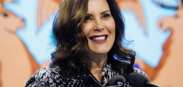 Gretchen Whitmer, Michigan Governor, smiles as she speaks into two microphones.