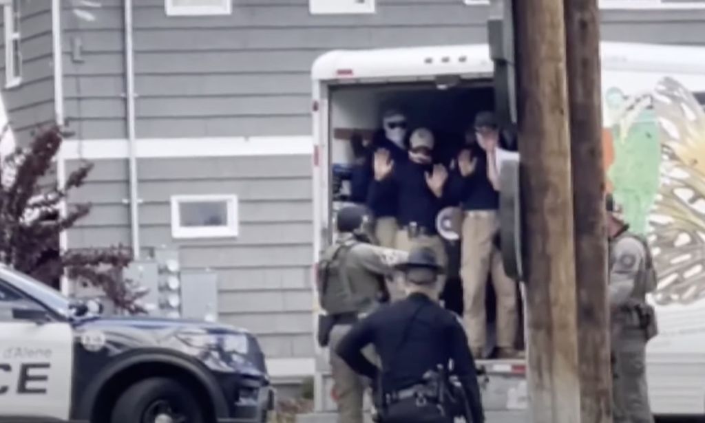 Members of Patriot Front hold up their hands as they stand in a U-Haul van and are arrested by police near a LGBTQ+ Pride event in Idaho