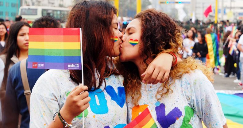 A couple kiss as they hold up rainbow LGBTQ+ Pride flags during a march in Peru where advocates call for same-sex marriage laws, for queer people to be protected from discrimination and more