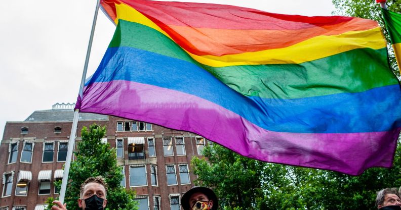 A person holds up a rainbow LGBTQ+ Pride flag