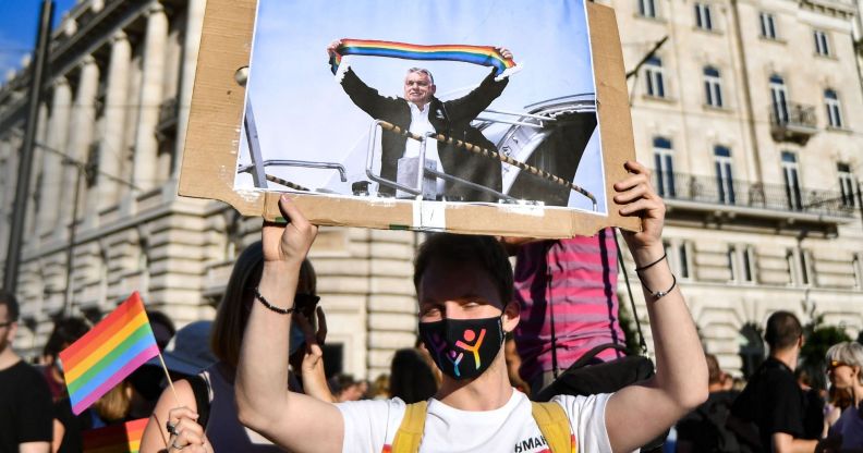 A person holds up a sign of Hungary's leader Viktor Orbán holding a rainbow scarf during an LGBTQ+ protest